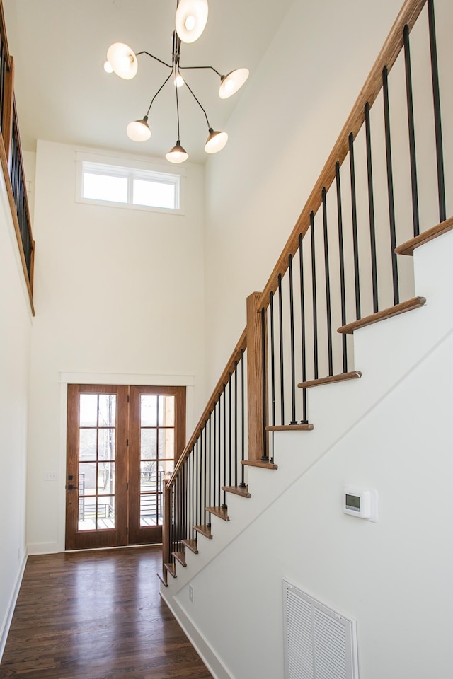 entryway featuring a notable chandelier, dark wood-type flooring, and a high ceiling