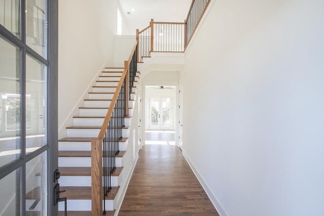 stairway with ceiling fan, a towering ceiling, wood-type flooring, and french doors