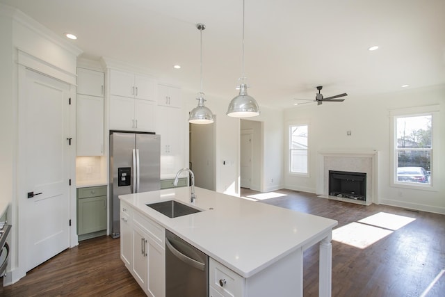 kitchen with sink, ceiling fan, stainless steel appliances, a center island with sink, and decorative backsplash