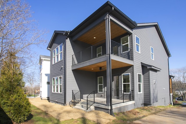 rear view of house featuring ceiling fan and a balcony