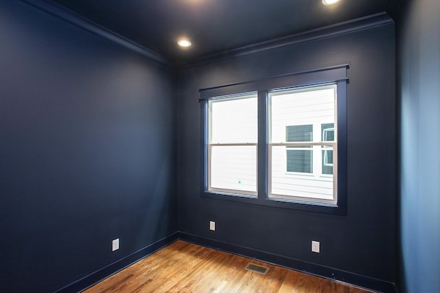 empty room featuring crown molding, wood-type flooring, and a healthy amount of sunlight