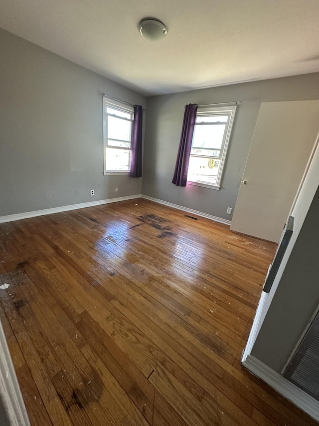 spare room with dark hardwood / wood-style flooring and a wealth of natural light