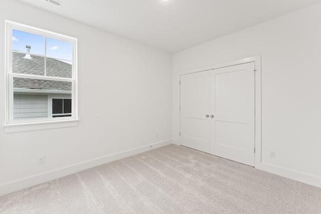 unfurnished bedroom with light colored carpet and a closet