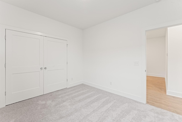 unfurnished bedroom with light colored carpet and a closet