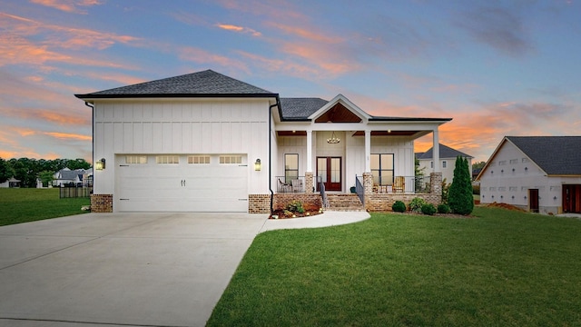 view of front of house featuring a porch, a yard, and a garage