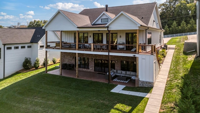 rear view of property with an outdoor living space, a balcony, a patio area, and a lawn