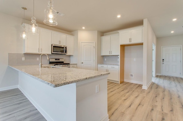 kitchen with white cabinetry, hanging light fixtures, stainless steel appliances, tasteful backsplash, and light wood-type flooring