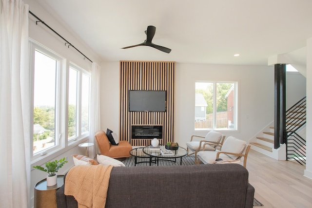 living room featuring plenty of natural light, ceiling fan, light wood-type flooring, and heating unit