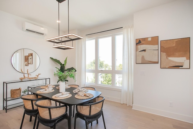 dining space featuring light wood-type flooring and a wall unit AC