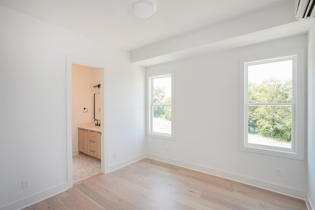 unfurnished room featuring a wall mounted air conditioner, light hardwood / wood-style floors, and sink