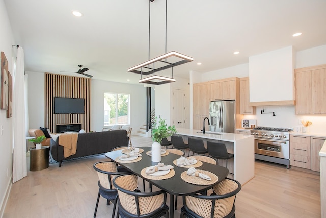 dining area with ceiling fan, light hardwood / wood-style floors, and sink