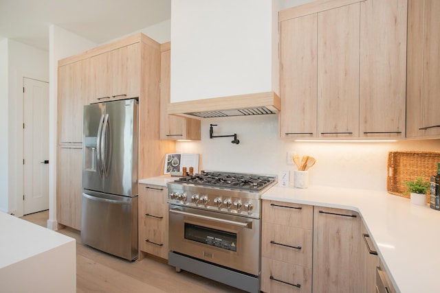 kitchen with light brown cabinetry, stainless steel appliances, and light hardwood / wood-style floors