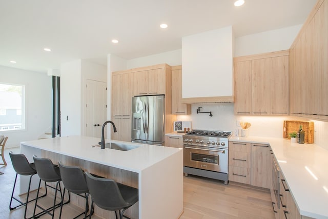 kitchen featuring a kitchen bar, sink, a center island with sink, and appliances with stainless steel finishes