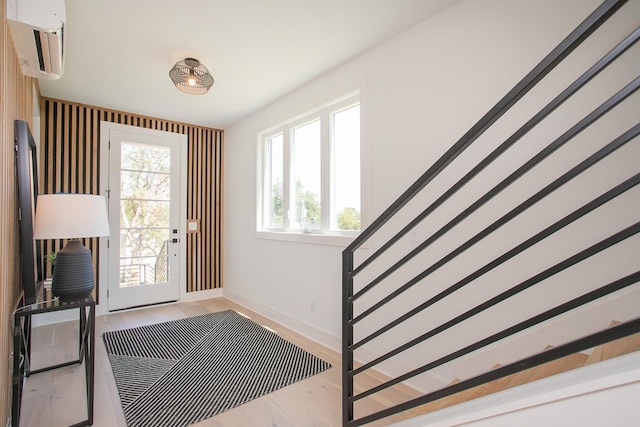 entryway with light hardwood / wood-style flooring and an AC wall unit