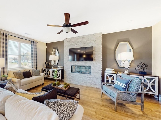 living room with a fireplace, light hardwood / wood-style flooring, and ceiling fan