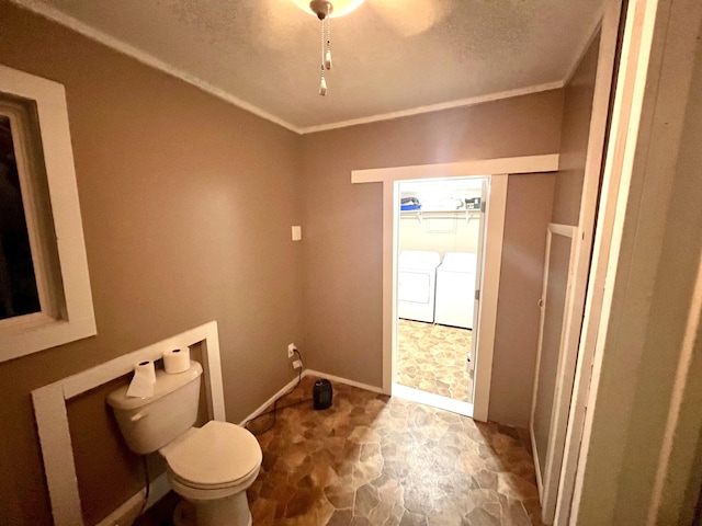 bathroom featuring toilet, washer and clothes dryer, and crown molding