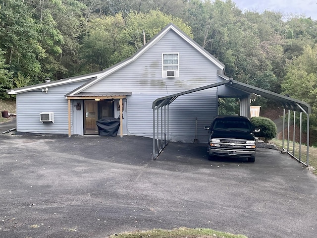 view of front facade with a carport and a wall mounted AC