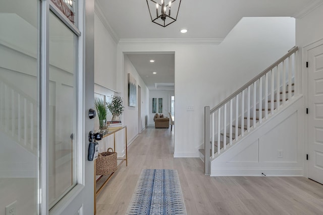 foyer featuring light wood-type flooring, an inviting chandelier, and ornamental molding