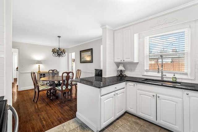 kitchen featuring sink, an inviting chandelier, pendant lighting, white cabinets, and ornamental molding