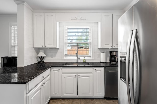 kitchen featuring white cabinetry, sink, stainless steel appliances, crown molding, and dark stone counters