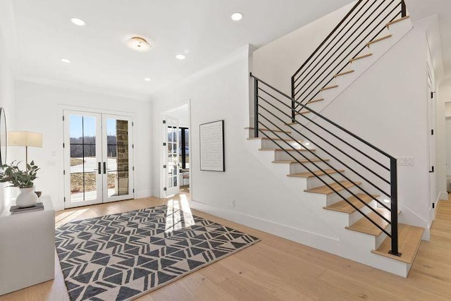 entrance foyer featuring french doors, ornamental molding, and light wood-type flooring