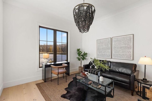 living room with wood-type flooring, an inviting chandelier, and crown molding