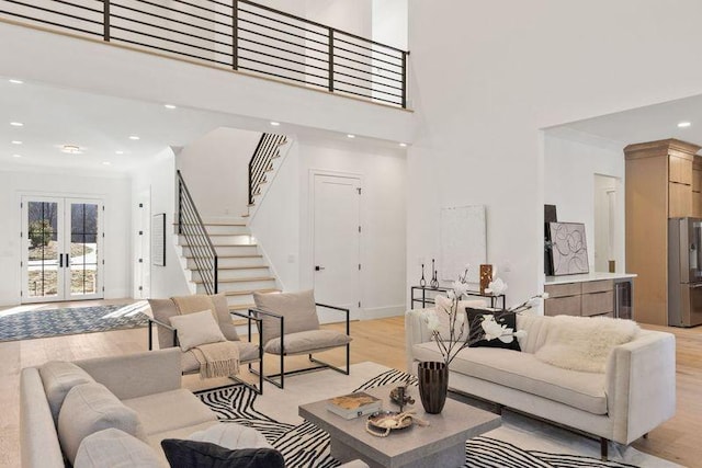 living room featuring a high ceiling, light hardwood / wood-style flooring, and french doors