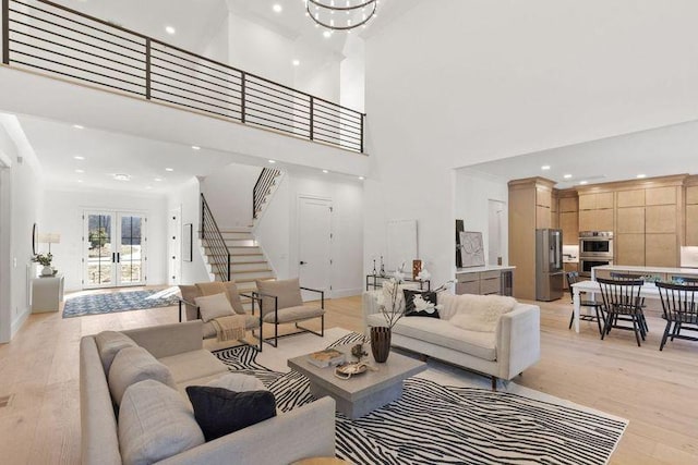 living room with french doors, an inviting chandelier, light wood-type flooring, and a high ceiling