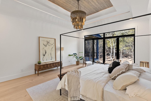 bedroom featuring a tray ceiling, wood-type flooring, and a chandelier