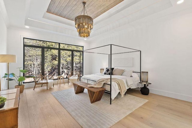 bedroom featuring a raised ceiling, a chandelier, and light wood-type flooring