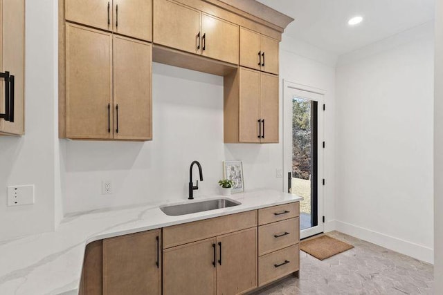 kitchen featuring light brown cabinetry, sink, and light stone countertops