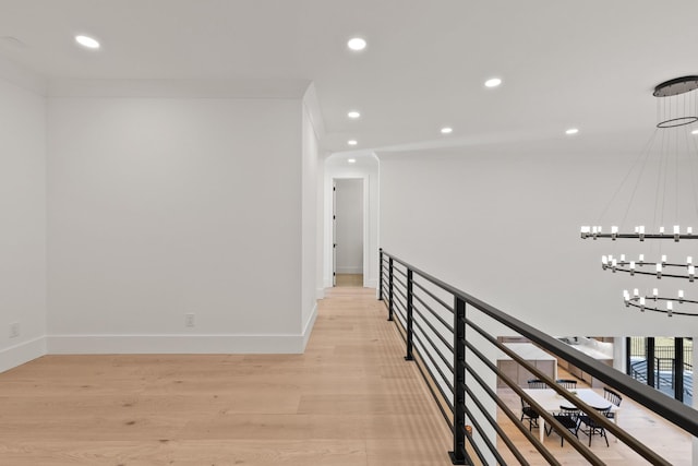 hallway with a notable chandelier and light wood-type flooring