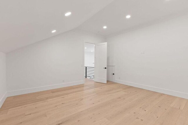 additional living space with vaulted ceiling and light hardwood / wood-style flooring