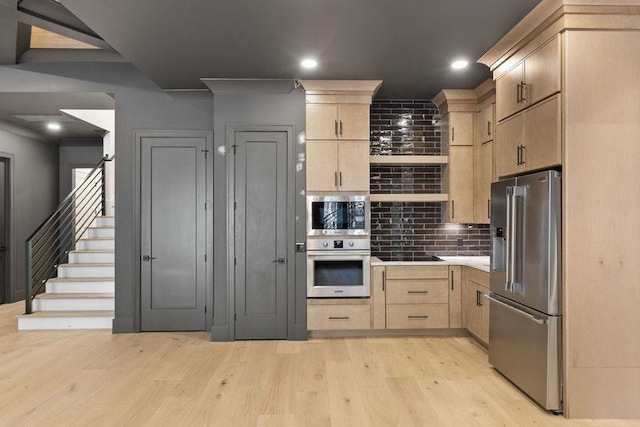 kitchen with light brown cabinetry, decorative backsplash, stainless steel appliances, and light hardwood / wood-style floors