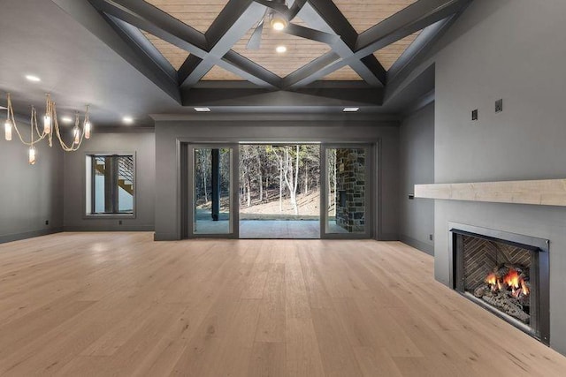 unfurnished living room featuring beamed ceiling, a notable chandelier, and light hardwood / wood-style floors