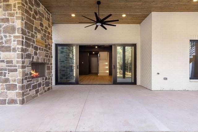 view of patio / terrace featuring ceiling fan and an outdoor stone fireplace