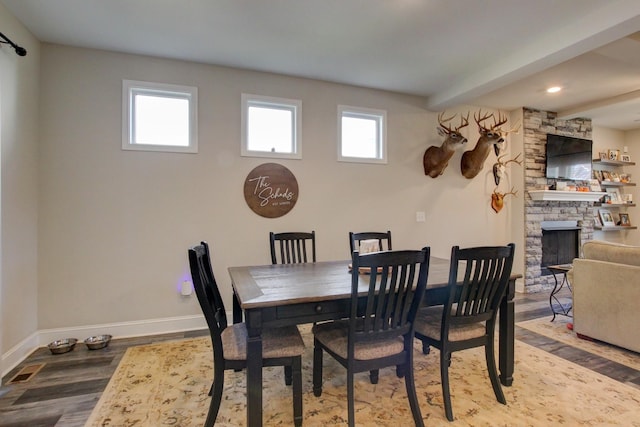 dining room featuring a stone fireplace and hardwood / wood-style flooring