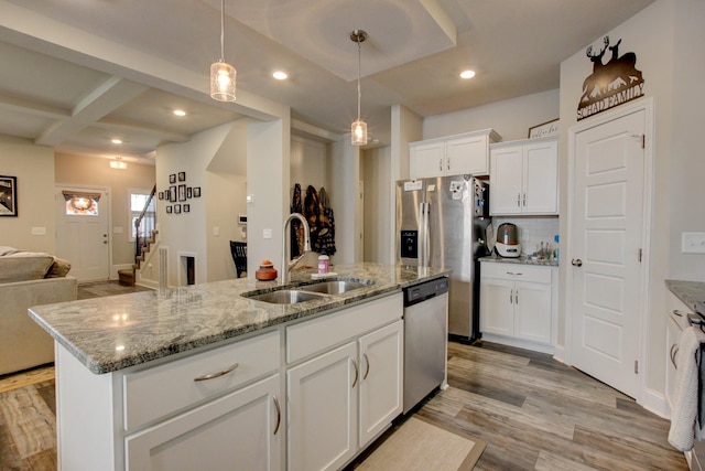 kitchen with a kitchen island with sink, white cabinets, hanging light fixtures, sink, and appliances with stainless steel finishes