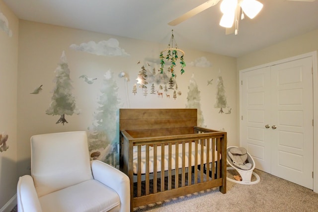 carpeted bedroom featuring ceiling fan, a closet, and a nursery area