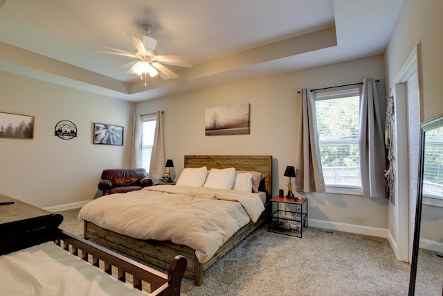 bedroom featuring light colored carpet, a raised ceiling, and ceiling fan