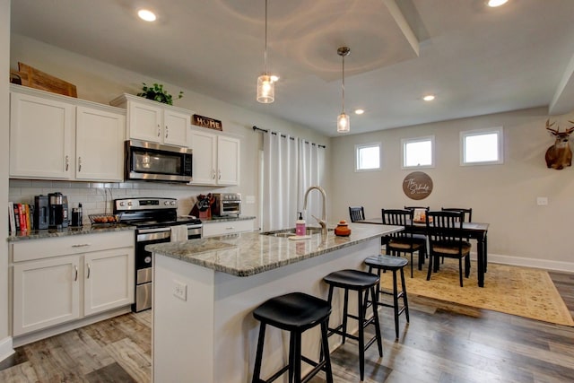 kitchen with white cabinets, appliances with stainless steel finishes, and a kitchen island with sink