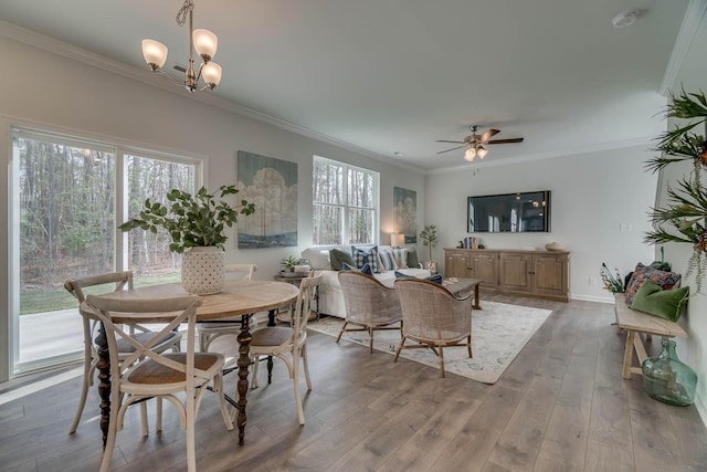 dining space with ceiling fan with notable chandelier, light hardwood / wood-style floors, and ornamental molding