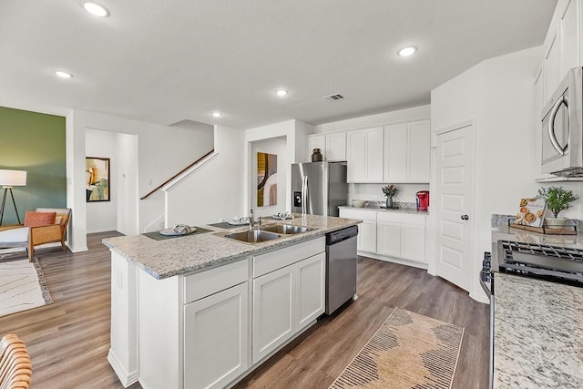 kitchen with a kitchen island with sink, dark hardwood / wood-style flooring, white cabinets, and stainless steel appliances