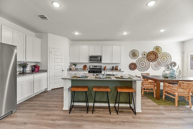 kitchen featuring a center island with sink, white cabinets, and stainless steel appliances