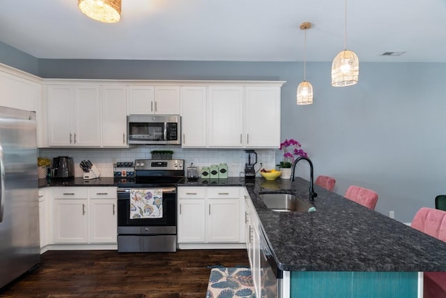 kitchen featuring white cabinets, hanging light fixtures, sink, and appliances with stainless steel finishes