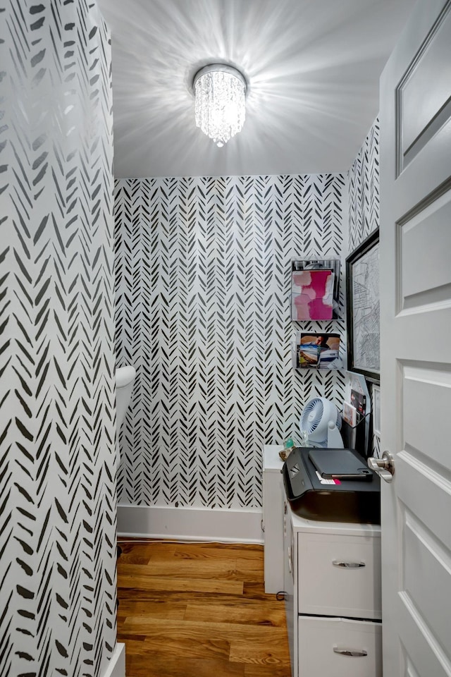 bathroom with wood-type flooring and an inviting chandelier