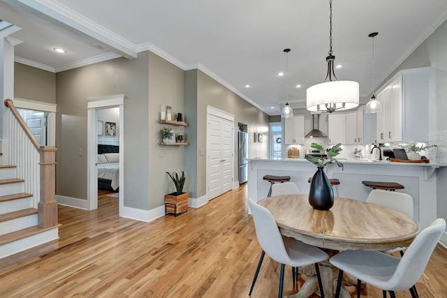 dining area featuring light wood-type flooring and crown molding