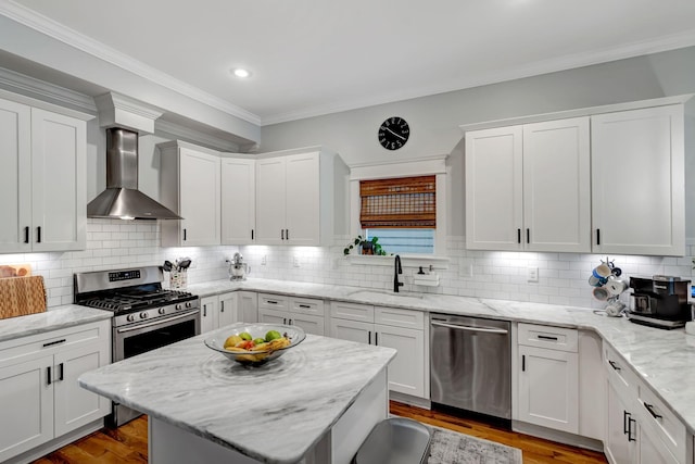 kitchen featuring tasteful backsplash, stainless steel appliances, sink, wall chimney range hood, and white cabinetry