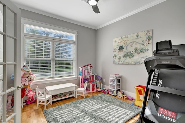 recreation room featuring ceiling fan, wood-type flooring, and crown molding