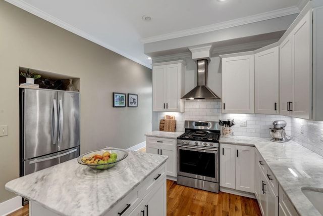 kitchen with white cabinetry, wall chimney range hood, light stone counters, hardwood / wood-style floors, and appliances with stainless steel finishes